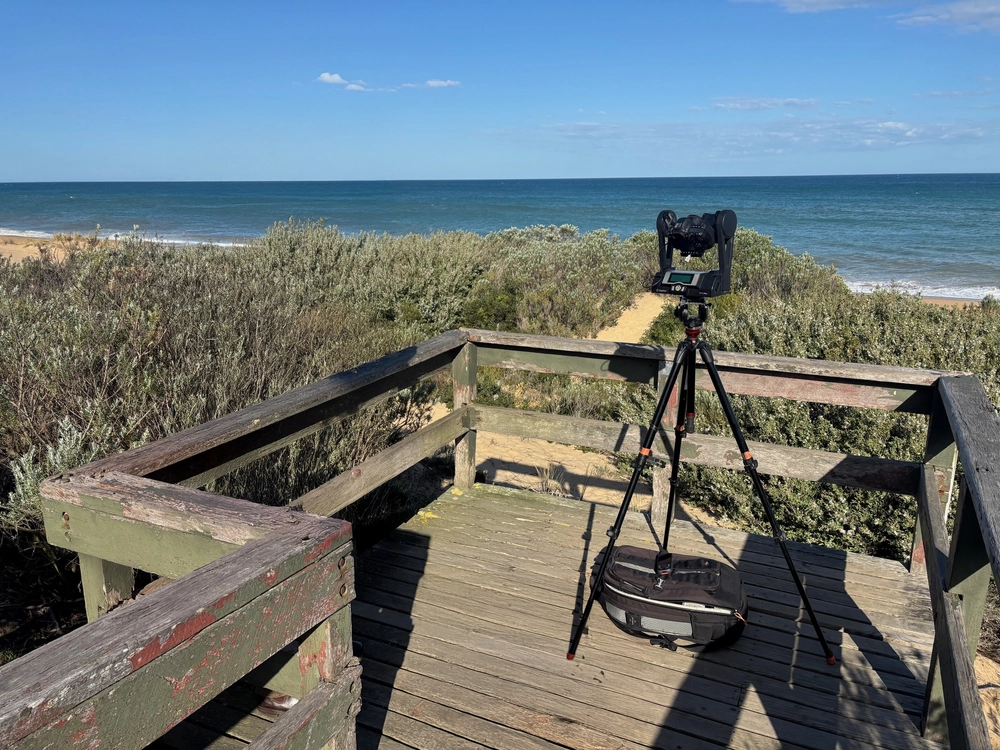 Camera on tripod on wooden deck overlooking beach and ocean